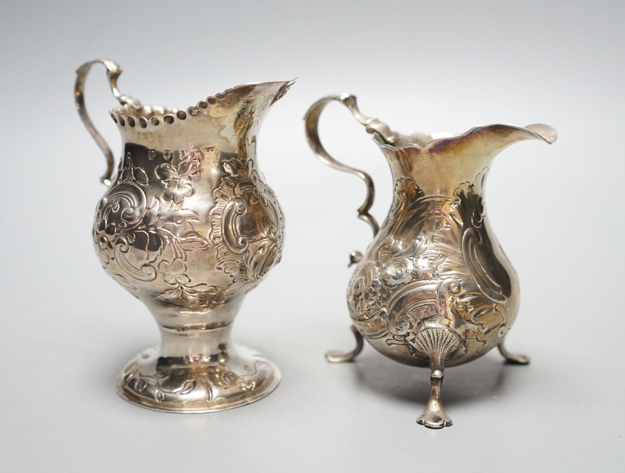 Two 18th century silver cream jugs, with later embossed decoration, London, 1753 & London, 1770, tallest 10.6cm, 174 grams.